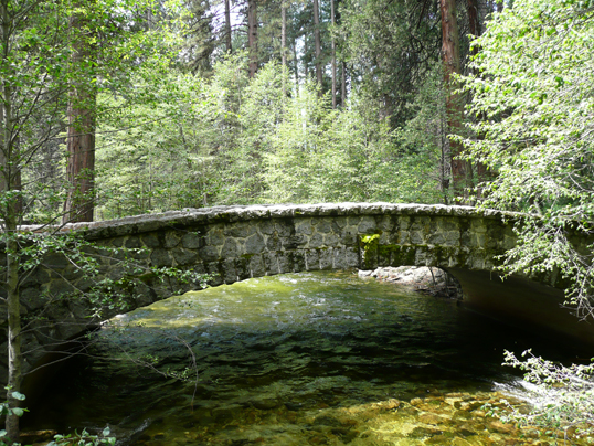 An old stone bridge over a stream in the woods